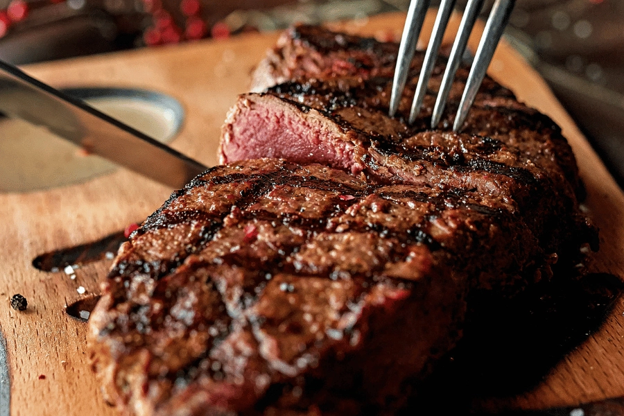 cutting a steak for dinner at a steakhouse on a cutting board